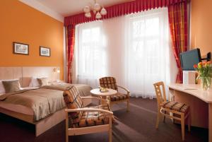 フランチシュコヴィ・ラーズニェにあるHotel Metropolのベッド、テーブル、椅子が備わるホテルルームです。