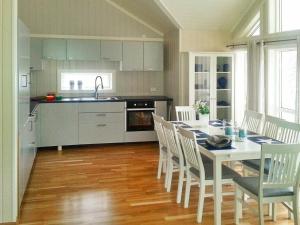 uma cozinha com uma mesa e cadeiras brancas e uma cozinha com um lavatório em 8 person holiday home in Tengelfjord em Tengelfjorden