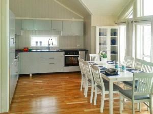 a kitchen with a white table and chairs and a kitchen with a sink at 8 person holiday home in Tengelfjord in Tengelfjorden