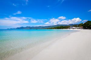 a white beach with the ocean and mountains in the background at Chaweng Garden Beach Resort - SHA Plus in Chaweng