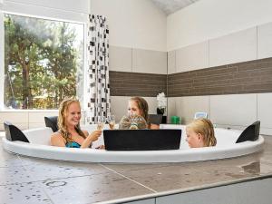 Tres mujeres sentadas en una bañera con ordenador portátil en 19 person holiday home in Nex, en Bedegård
