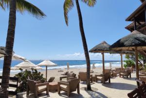 Una playa con sillas y sombrillas y el océano. en Le Saint Alexis **** Hotel & Spa, en Saint-Gilles-les-Bains