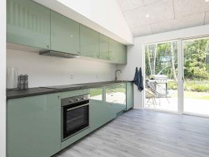 a kitchen with green cabinets and a large window at 8 person holiday home in L s in Læsø