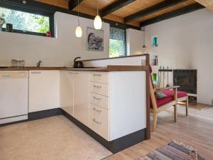 a kitchen with white cabinets and a red chair at 6 person holiday home in Knebel-By Traum in Skødshoved Strand +12 photos