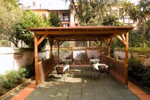 une pergola en bois avec des chaises et des tables sur une terrasse dans l'établissement Hotel Sabatino Milan, à Milan