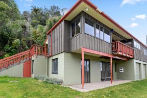 a house with a balcony on the side of it at Escape to the Lake - Lake Rotoiti Bach in Okere Falls