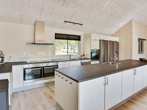 a kitchen with white cabinets and a black counter top at 20 person holiday home in Vejby in Vejby