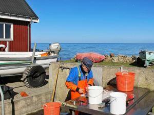 a man in an orange vest working on a table with buckets at 6 person holiday home in Str by in Strøby