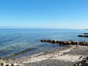 a beach with rocks and the ocean on a clear day at 6 person holiday home in Str by in Strøby
