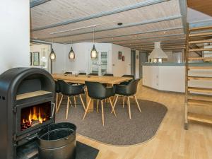 a dining room with a fireplace and a table and chairs at 14 person holiday home in R m in Kongsmark