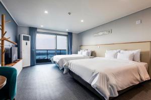 a hotel room with two beds and a television at Aewol Stay in Jeju Hotel&Resort in Jeju