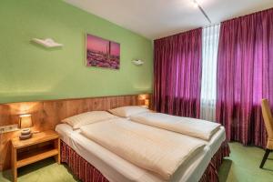 a bedroom with a large bed with purple curtains at Hotel Arosa Düsseldorf Oberkassel in Düsseldorf