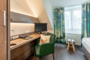 Zimmer mit einem Schreibtisch mit einem Computer und einem grünen Stuhl in der Unterkunft Hotel Arosa Düsseldorf Oberkassel in Düsseldorf