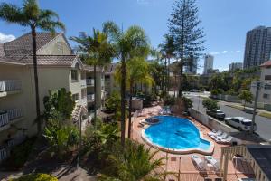 un apartamento con piscina, palmeras y un edificio en Surfers Tradewinds, en Gold Coast