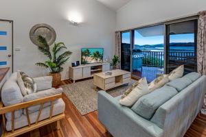a living room with two couches and a balcony at Casuarina 18 Ocean View House Central Location BBQ Golf Buggy in Hamilton Island