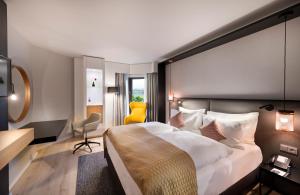 ein Hotelzimmer mit einem großen Bett und einem gelben Stuhl in der Unterkunft Crowne Plaza Düsseldorf - Neuss, ein IHG Hotel in Neuss
