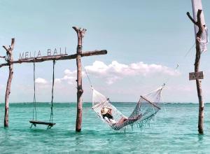 een vrouw zit in een hangmat in de oceaan bij Melia Bali in Nusa Dua