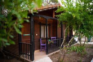 Ce chalet en bois dispose d'une terrasse couverte et d'un fauteuil violet. dans l'établissement Koala Bungalows, à Olympos