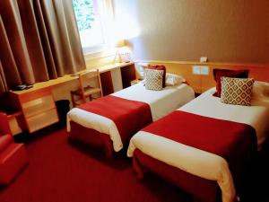 um quarto de hotel com duas camas e uma janela em Hôtel Logis Atrium Epinal Golbey Chavelot em Épinal