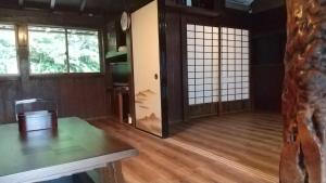 築100年の宿【はぶの家】 في Oshima: غرفة مع أرضية خشبية وباب زجاجي منزلق