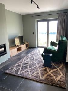 ein Wohnzimmer mit einem grünen Stuhl und einem Teppich in der Unterkunft XXV House - 12 personnes in Héron