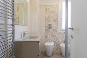 a white bathroom with a toilet and a sink at Appartamento Birba e Sgrinfia in Lido di Ostia