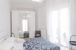 a white bedroom with a bed and a mirror at Appartamento Birba e Sgrinfia in Lido di Ostia