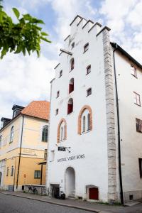 a white building with red windows on a street at Hotell Visby Börs in Visby
