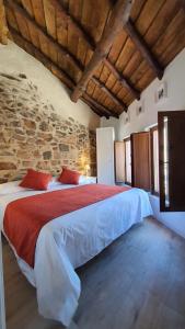 um quarto com uma cama grande numa parede de pedra em Casas del Castillo, 3 em Ávila
