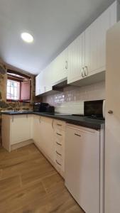 Una cocina con gabinetes blancos y una encimera negra. en Casas del Castillo, 3, en Ávila