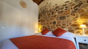 Un dormitorio con una cama con una pared de piedra. en Casas del Castillo, 3, en Ávila
