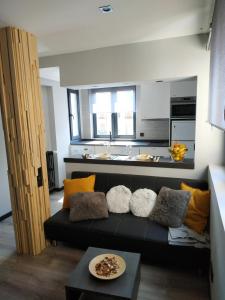 sala de estar con sofá negro y cocina en La Afayaíza en Oviedo