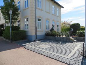 a white house with a brick sidewalk in front of it at Skerra Apartments "am Fitness-Studio" in Fehmarn