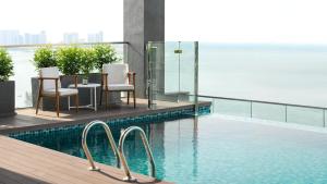 una piscina con sillas y vistas al agua en OZO George Town Penang en George Town