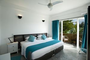 a bedroom with a large bed and a balcony at Boutique Beach All Inclusive Diving Hotel in Dhigurah