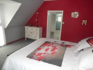 een slaapkamer met een groot bed met een rode muur bij Faré Flammek in Dinard