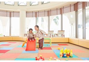 un hombre y una niña jugando en un patio de recreo en Hotel Mahaina Wellness Resorts Okinawa, en Motobu