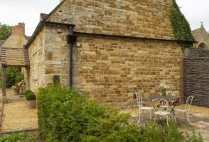 a brick building with a table and chairs in front of it at Kitchen Garden Cottage in Barton