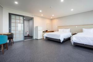 a hotel room with two beds and a refrigerator at Aewol Stay in Jeju Hotel&Resort in Jeju