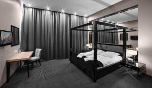 sypialnia z czarnym łóżkiem piętrowym, biurkiem i biurkiem w obiekcie Focus Hotel Premium Elbląg w Elblągu