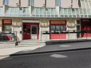 een gebouw met een rode deur en een hotel bij Hôtel Hermance in Bellegarde-sur-Valserine
