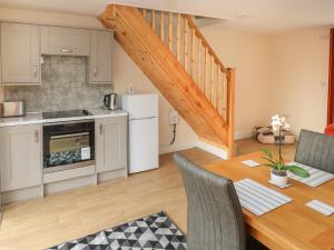 uma cozinha e sala de jantar com uma mesa e uma cozinha e escadas em Nuthatch Barn em Pontyclun