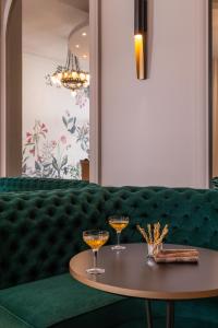 a green couch with two glasses on a table at Leonardo Boutique Hotel Paris Opera in Paris