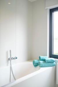 a white bath tub with two blue towels on it at Fabulous 4 bedrooms villa near Zwin with a garden in Knokke-Heist