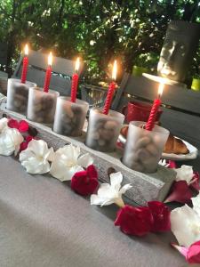 un groupe de bougies sur une table avec des fleurs rouges et blanches dans l'établissement Chambres d'Hôtes et Gîtes Le Mas Mellou, à Orange