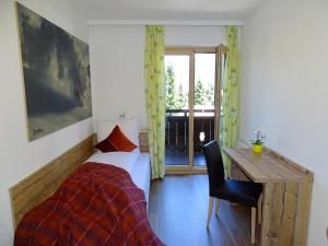 a bedroom with a bed and a desk and a window at Appartementhaus Mayrhofen by PiaundDirk in Mayrhofen