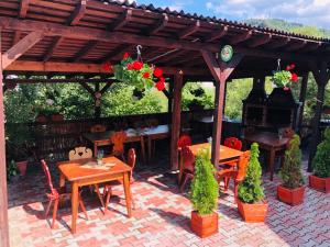 a patio with tables and chairs and a wooden pergola at Pensiunea Ioana in Borşa