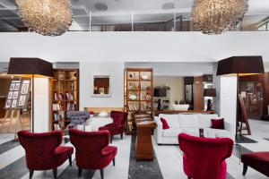 a living room with a white couch and red chairs at Focus Hotel Premium Elbląg in Elblag
