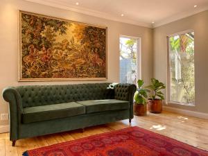 a living room with a green couch and a large painting at Murray Street 137 Guesthouse in Pretoria