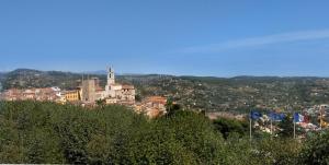 a town on top of a hill with flags at Hotel Panorama in Grasse